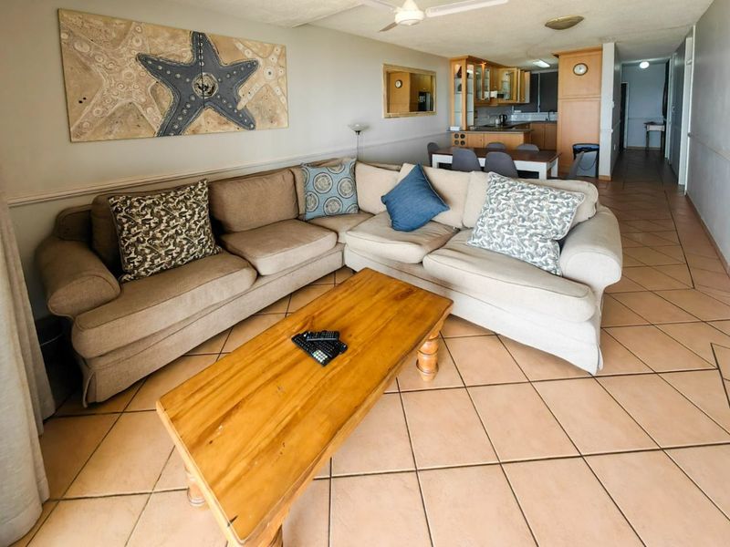Open-plan living and dining area featuring ceramic floor tiles, a ceiling fan, and an adjacent kitchen with built-in cabinetry.