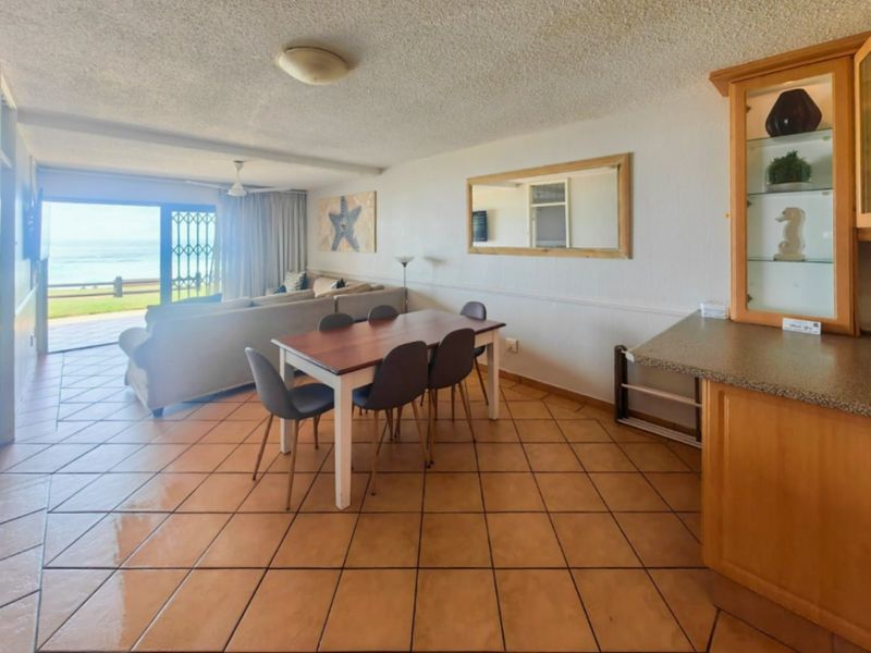 Open plan living and dining area featuring tiled flooring, built-in cabinetry, and direct access to a patio with ocean views.
