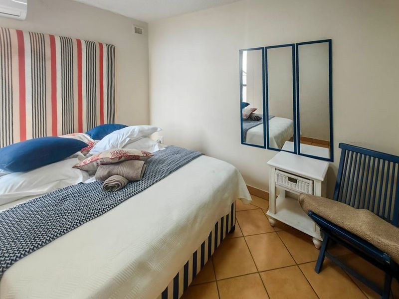 A bedroom featuring tiled flooring and a wall-mounted air conditioning unit.