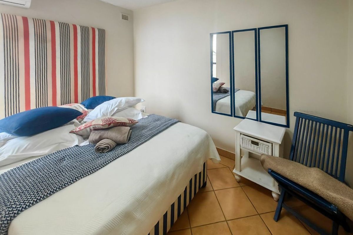 A bedroom featuring tiled flooring and a wall-mounted air conditioning unit.