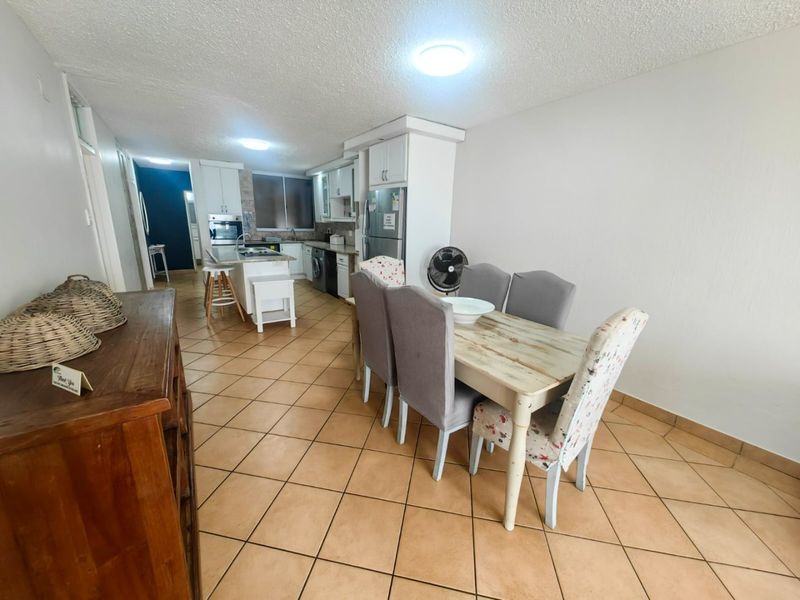 Open plan kitchen and dining area featuring tiled flooring, white cabinetry, and a central kitchen island.