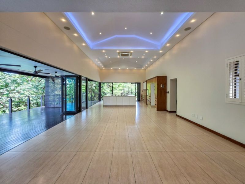Spacious open-plan living and kitchen area featuring a tray ceiling with ambient lighting, large stacking glass doors, and a central kitchen island.