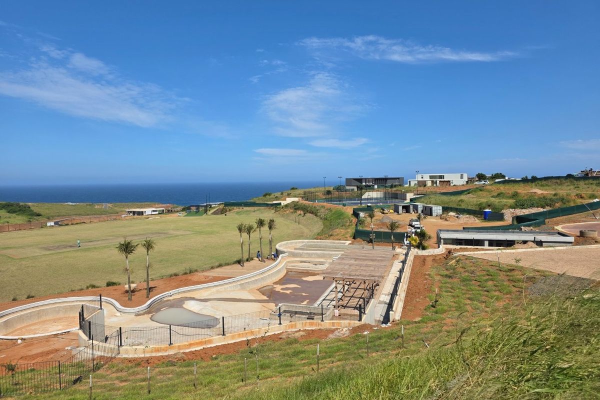 Aerial view of a residential development site featuring an under-construction swimming pool, retaining walls, and expansive coastal landscape views.