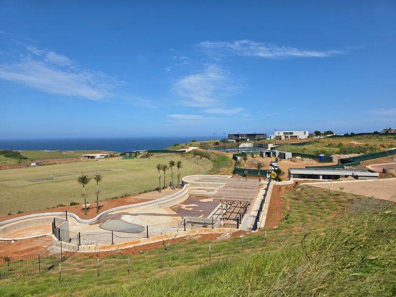 Aerial view of a residential development site featuring an under-construction swimming pool, retaining walls, and expansive coastal landscape views.