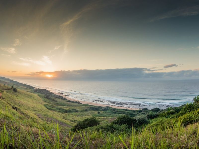 A panoramic view of the coastline and ocean at sunset, showcasing the natural landscape of the vacant land property.