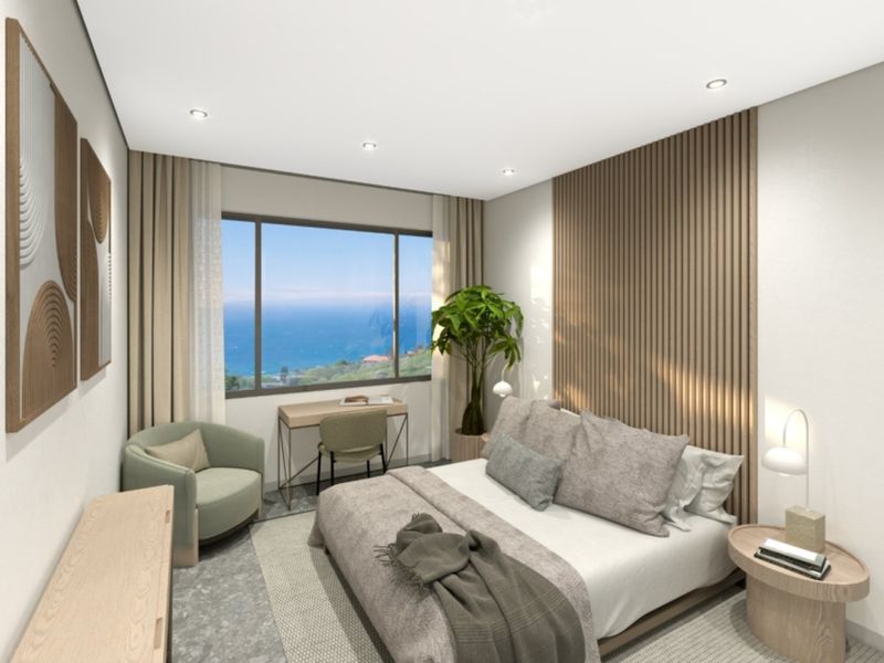 Modern bedroom featuring a timber slat feature wall, recessed lighting, and a large window offering scenic ocean views.