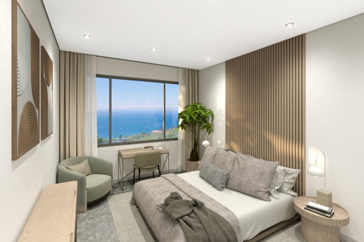 Modern bedroom featuring a timber slat feature wall, recessed lighting, and a large window offering scenic ocean views.