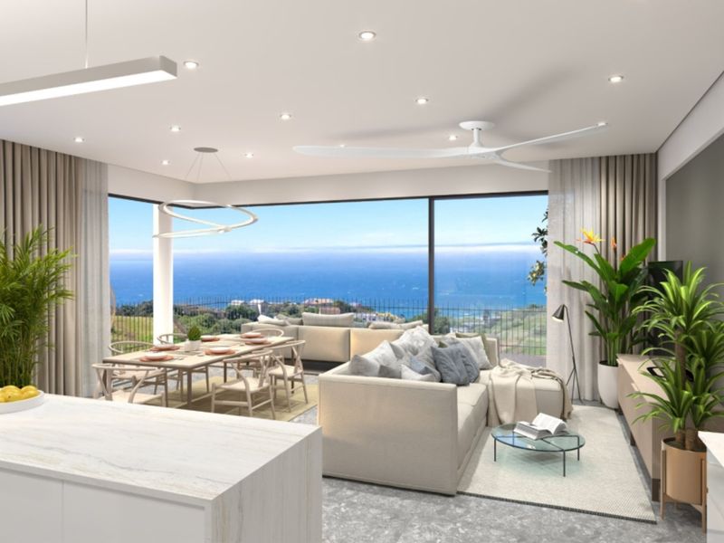 Modern open-plan living and dining area featuring a kitchen island, recessed lighting, and expansive sliding glass doors showcasing a panoramic ocean view.