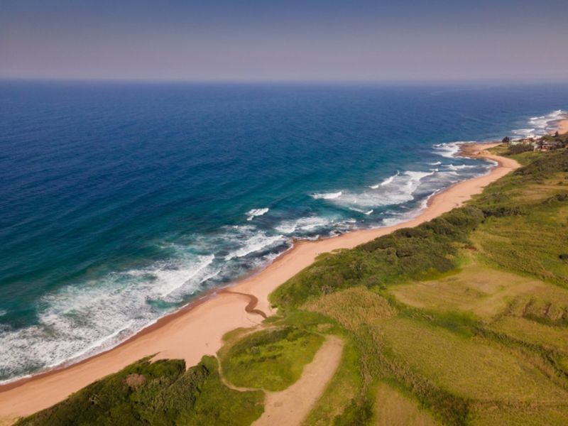 An aerial view of the coastal landscape and beachfront, showcasing the natural terrain and proximity to the ocean.