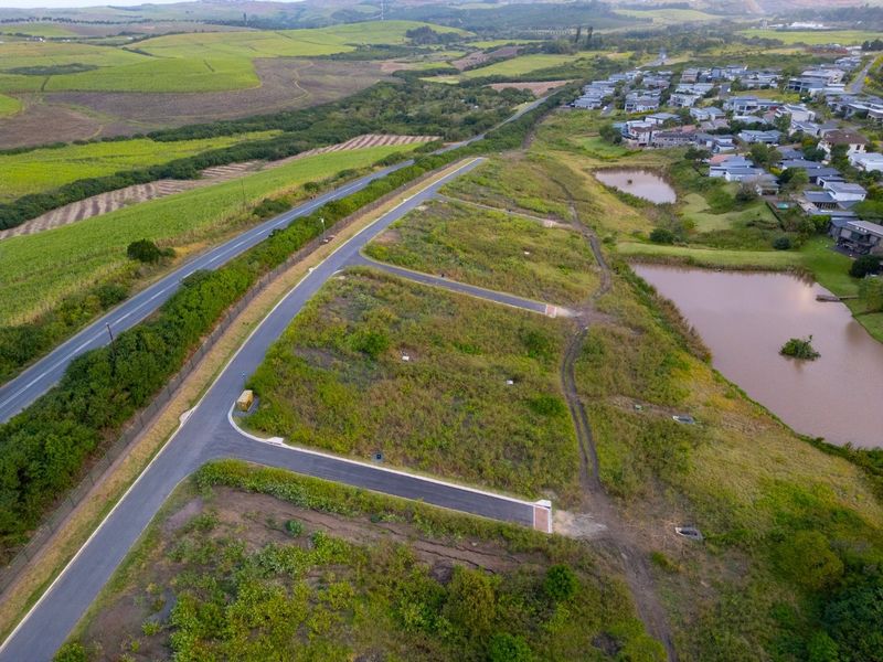Aerial view of a residential land development featuring paved access roads, utility connections, and proximity to local water features and surrounding landscape.