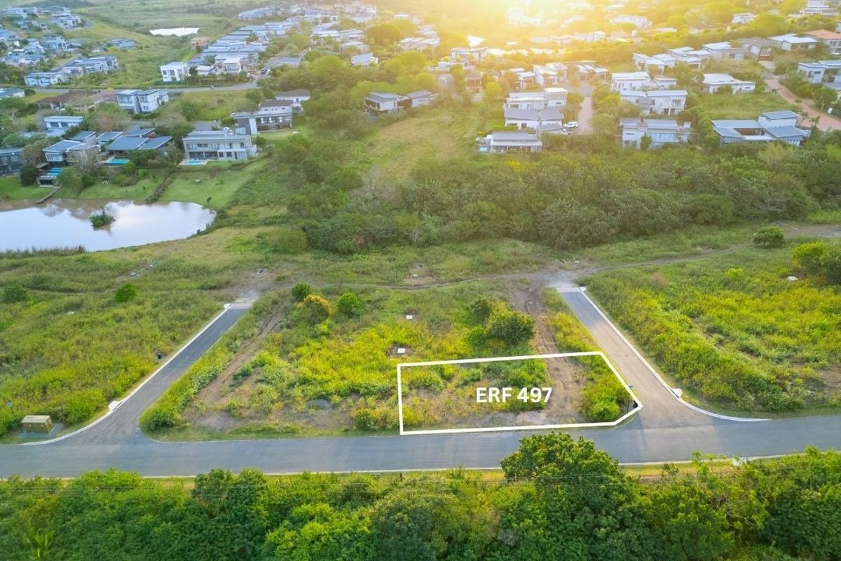 An aerial view of a vacant residential plot, Erf 497, situated within a developed estate with established road access and surrounding greenery.