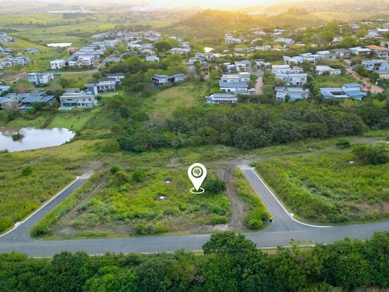 Aerial view of a vacant residential plot featuring established road access and utility connections within a developed estate setting.