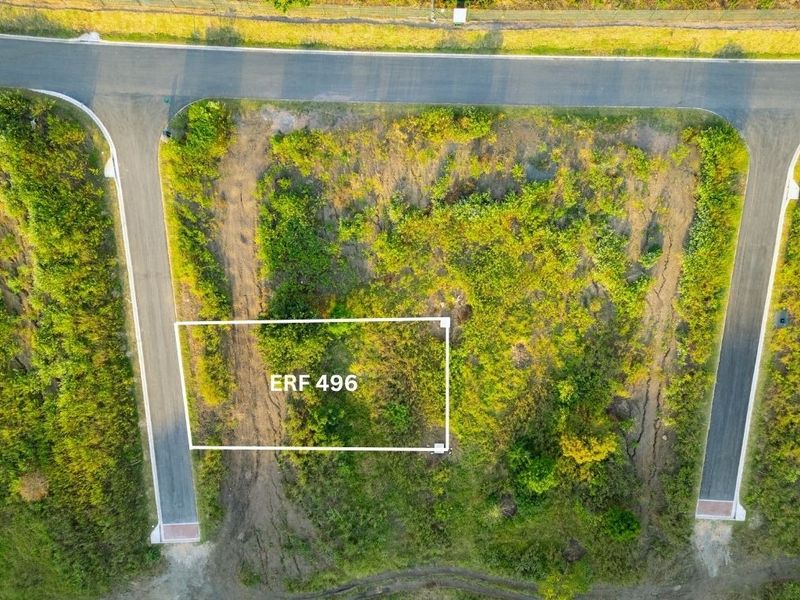Aerial view of a vacant residential plot, Erf 496, featuring direct access to paved roads and surrounding natural vegetation.