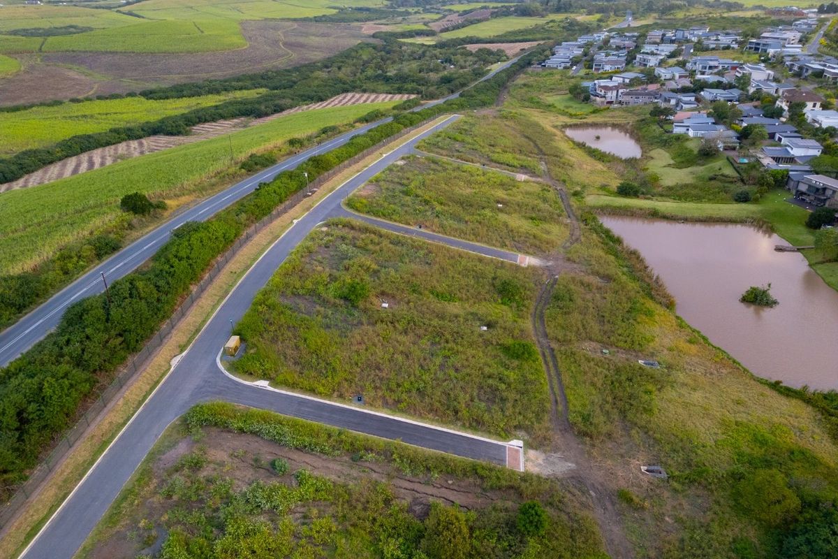 Aerial view of a residential land development featuring paved access roads, utility connections, and proximity to local water features and surrounding landscape.