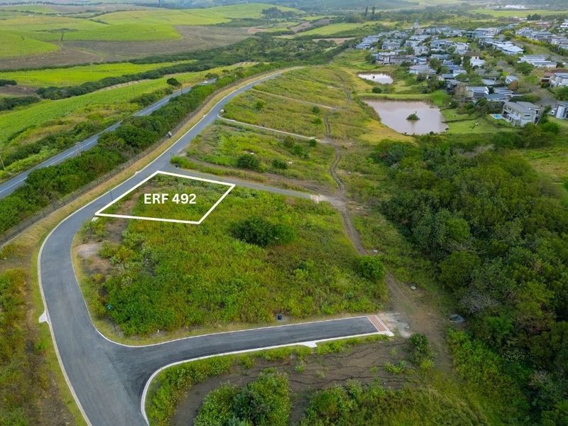 Aerial view of a vacant residential plot, ERF 492, situated in a developing estate with established road infrastructure and surrounding greenery.
