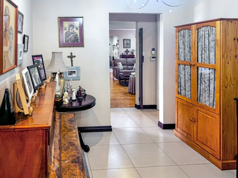 A tiled hallway connecting to an adjacent living area with timber flooring, featuring neutral wall finishes and standard architectural transitions.