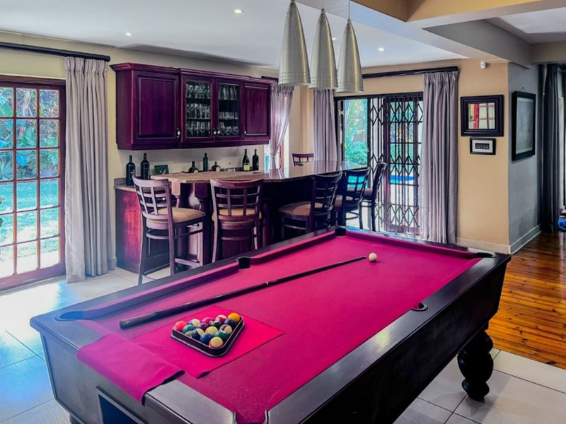 A dedicated entertainment bar area featuring built-in cabinetry, pendant lighting, and direct access to the garden through sliding glass doors.