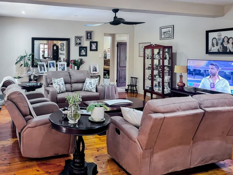 A comfortable living room featuring polished hardwood flooring, a ceiling fan, and recessed lighting, providing a warm and inviting atmosphere.