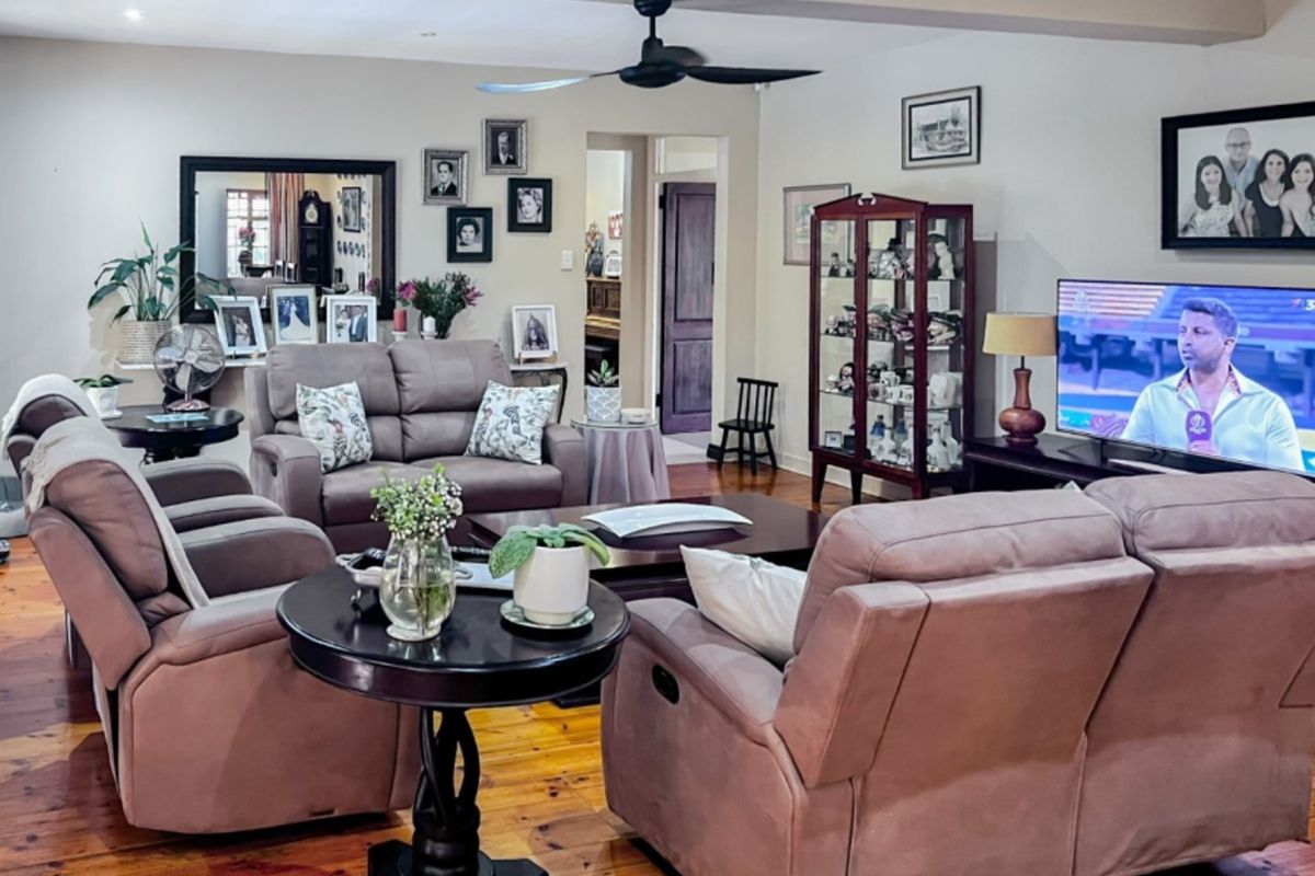 A comfortable living room featuring polished hardwood flooring, a ceiling fan, and recessed lighting, providing a warm and inviting atmosphere.