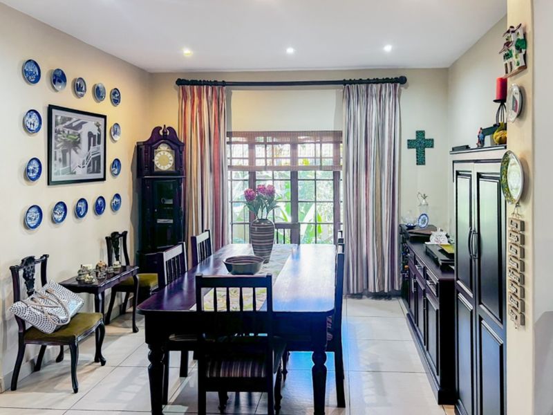 A formal dining room featuring tiled flooring, recessed lighting, and large windows with curtain treatments, providing a bright and functional space for meals.