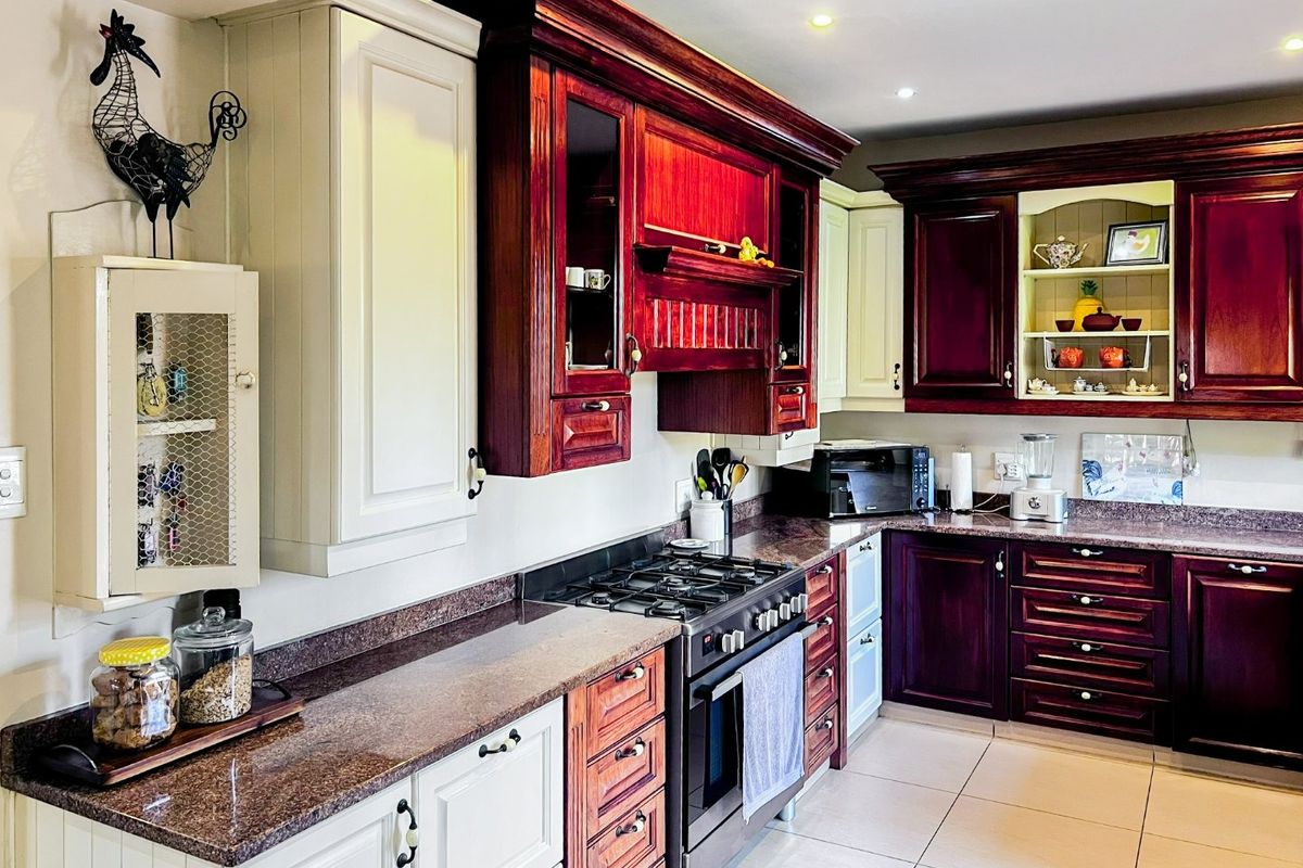 A well-maintained kitchen featuring two-tone cabinetry, granite countertops, a gas stove with oven, and recessed lighting.