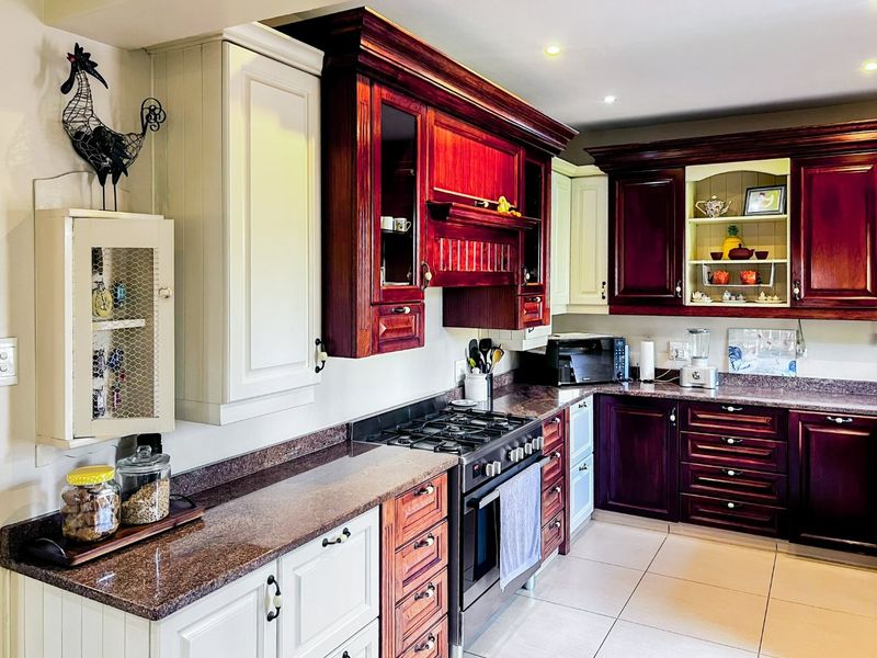 A well-maintained kitchen featuring two-tone cabinetry, granite countertops, a gas stove with oven, and recessed lighting.
