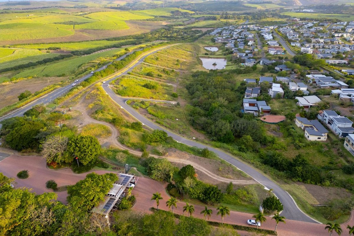 Aerial view of a residential estate featuring paved roads, landscaped surroundings, and proximity to surrounding greenbelt areas and existing housing developments.