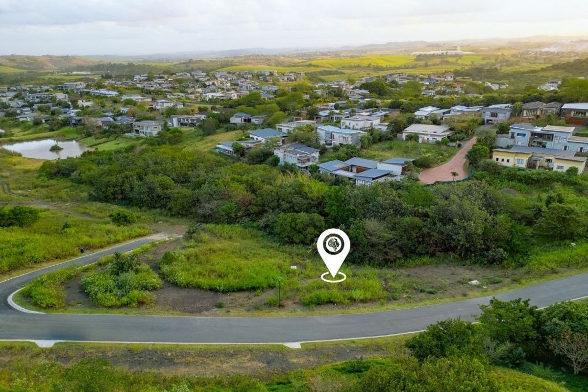 Aerial view of a vacant residential land plot situated within a developed estate, featuring surrounding greenery and established road infrastructure.