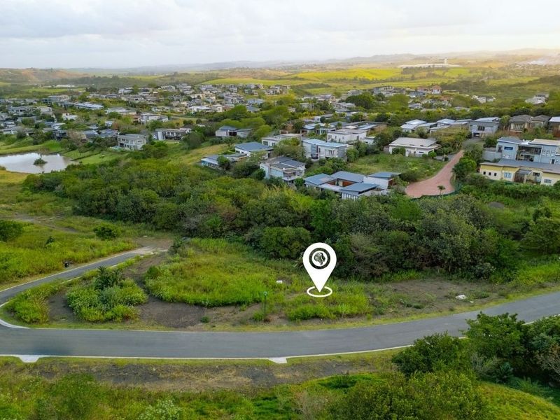 Aerial view of a vacant residential land plot situated within a developed estate, featuring surrounding greenery and established road infrastructure.