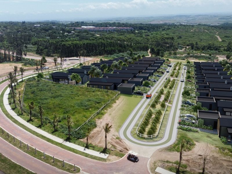 Aerial view of a modern residential housing development featuring uniform dark-roofed homes, paved access roads, and landscaped surroundings within a gated estate.