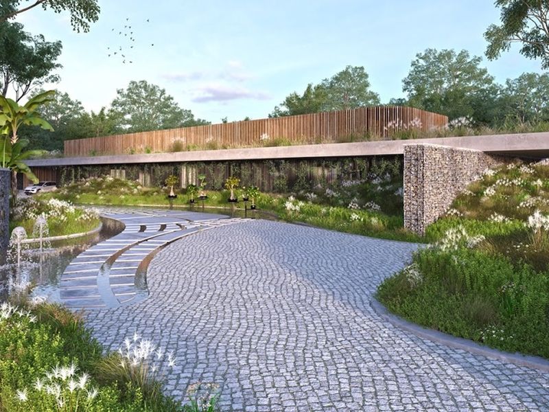 A modern architectural entrance featuring a cobblestone driveway, gabion stone walls, and a landscaped water feature with fountains.