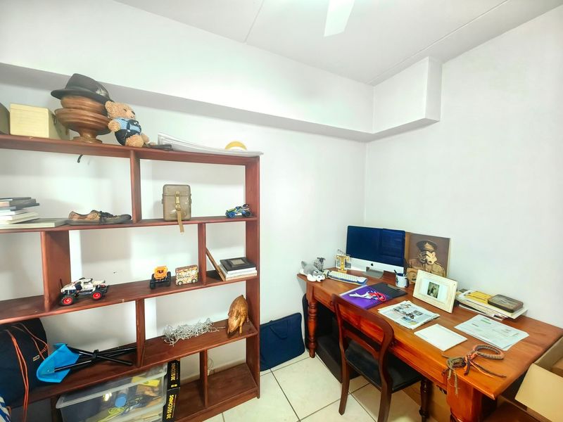 A functional home office space featuring tiled flooring and a ceiling fan, providing a dedicated area for work or study.