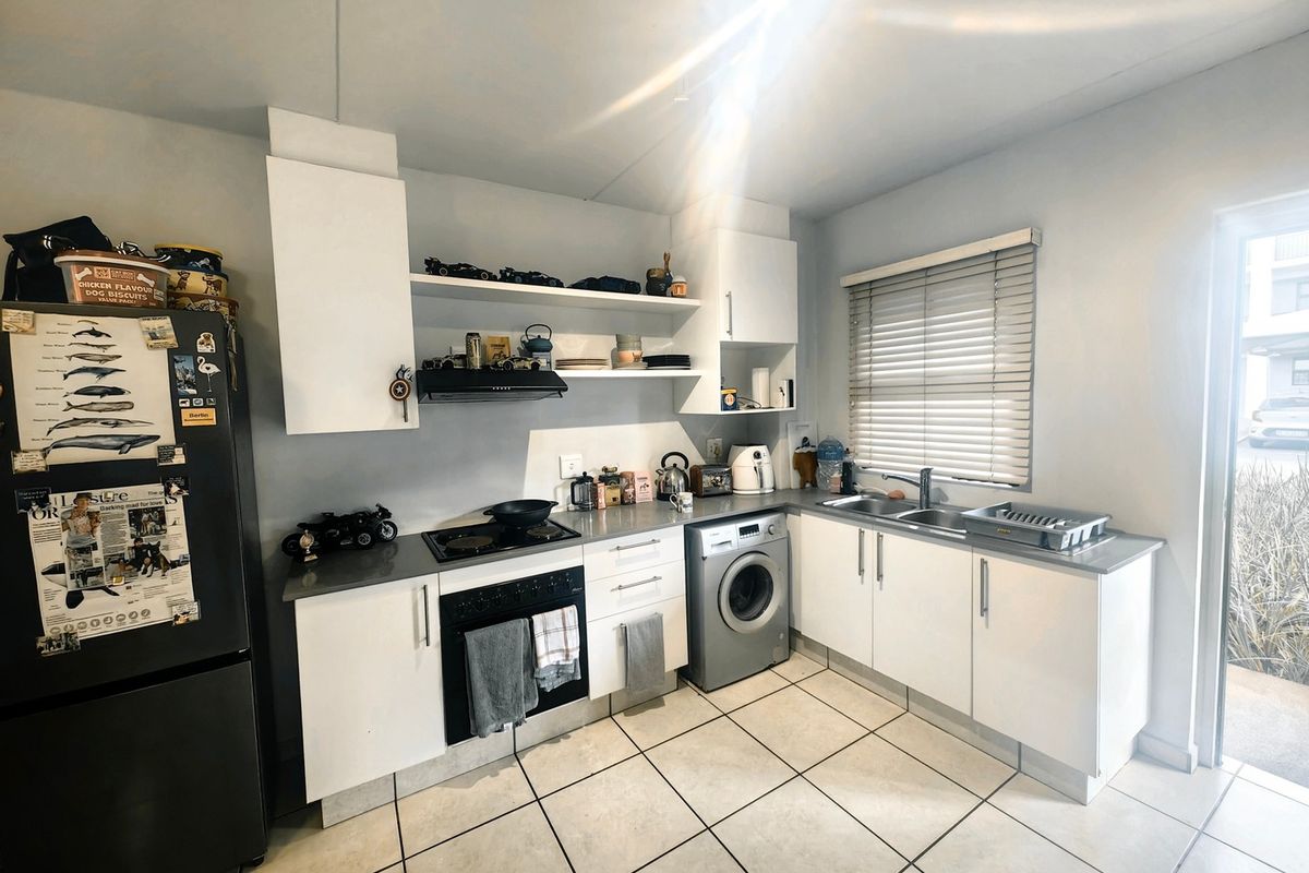 Functional kitchen featuring white cabinetry, laminate countertops, integrated oven and hob, tiled flooring, and direct access to an outdoor area.