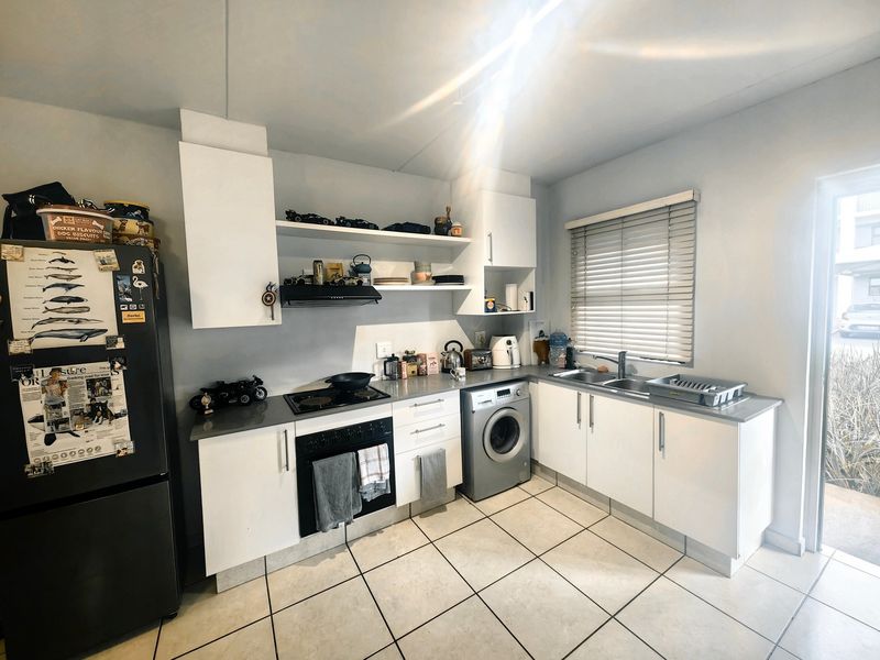 Functional kitchen featuring white cabinetry, laminate countertops, integrated oven and hob, tiled flooring, and direct access to an outdoor area.