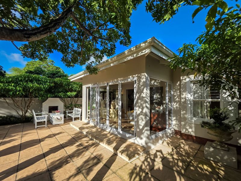 A well-maintained covered patio area featuring tiled flooring, a built-in fireplace, and large folding glass doors providing seamless access to the interior living space.