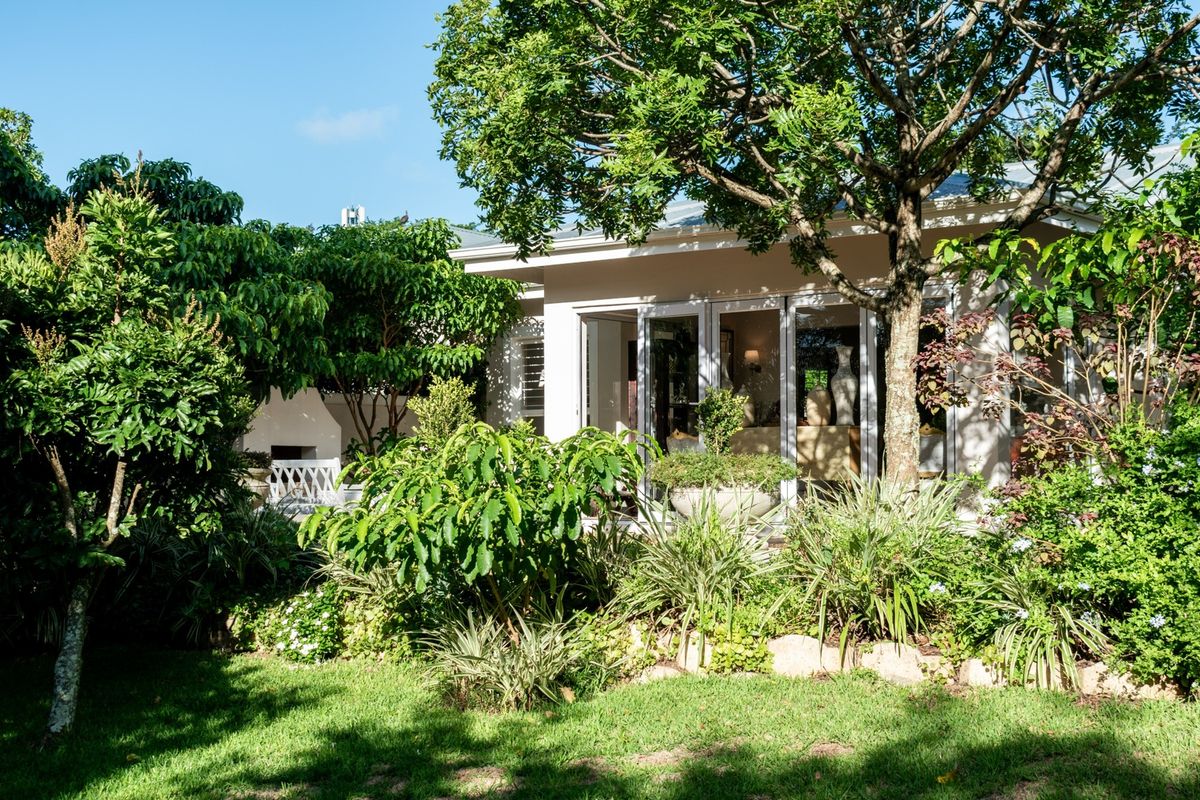 A lush rear garden featuring a built-in braai area and folding glass doors that provide seamless access to the interior living space.