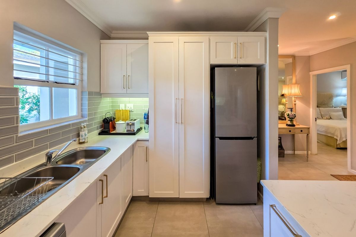 Modern kitchen featuring white cabinetry, stone countertops, subway tile backsplash, and a double basin sink with contemporary finishes.