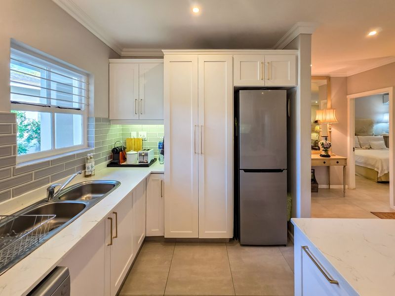 Modern kitchen featuring white cabinetry, stone countertops, subway tile backsplash, and a double basin sink with contemporary finishes.