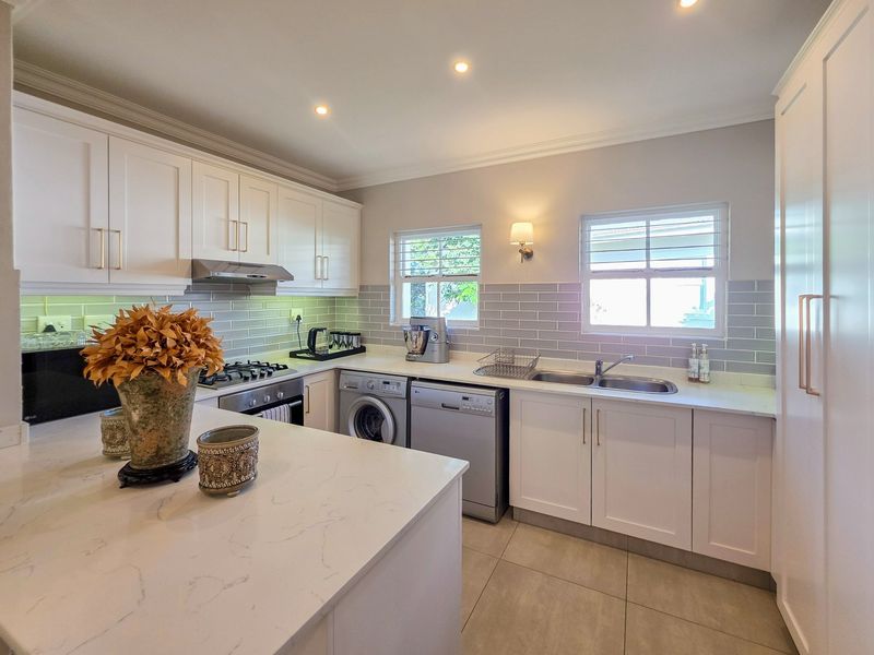 Modern kitchen featuring white cabinetry, stone countertops, a central island, subway tile backsplash, and integrated appliances including a gas hob and oven.