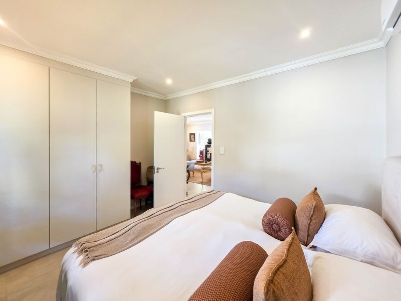 A well-maintained bedroom featuring neutral walls, built-in cupboards, recessed downlighting, and crown molding, offering a clean and comfortable living space.