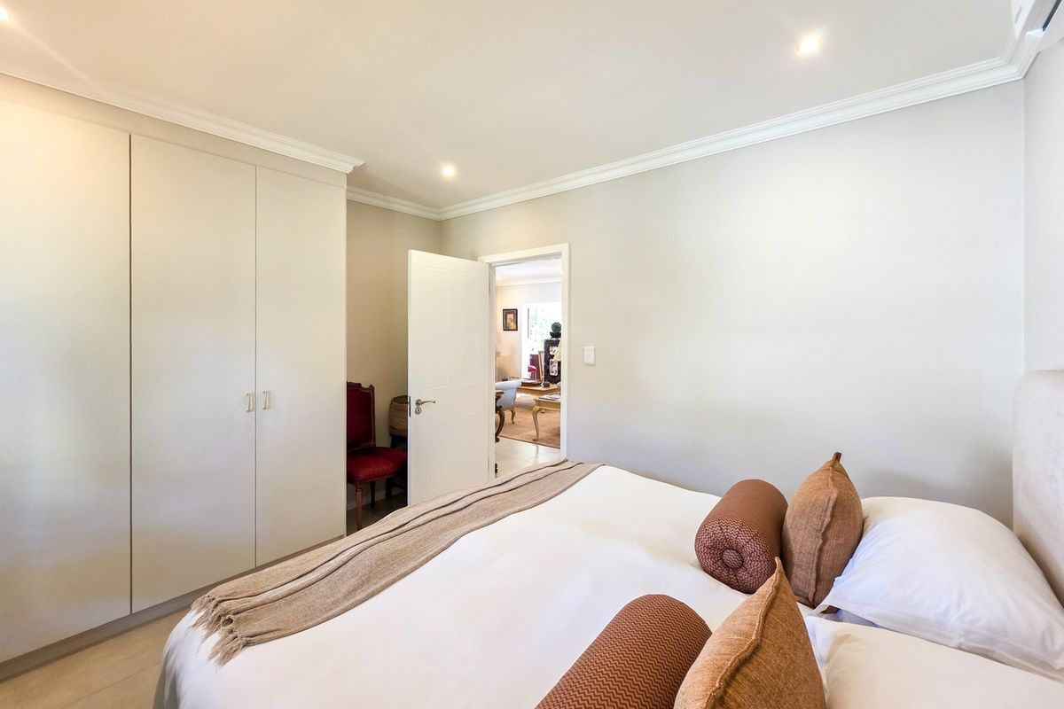A well-maintained bedroom featuring neutral walls, built-in cupboards, recessed downlighting, and crown molding, offering a clean and comfortable living space.
