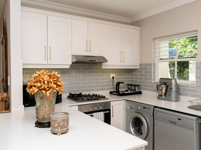 Modern kitchen featuring white shaker cabinetry, quartz countertops, subway tile backsplash, and integrated appliances including a gas hob and oven.