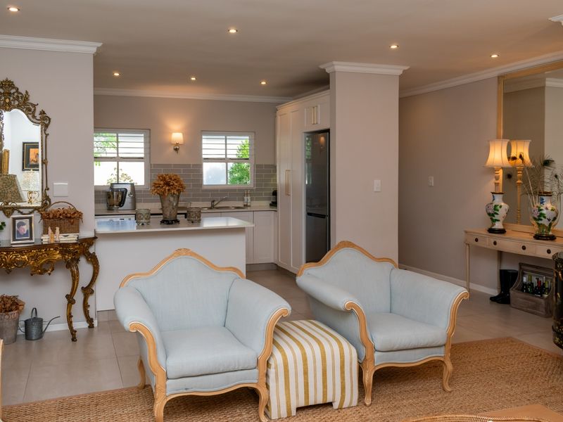 An elegant open-plan living and kitchen area featuring tiled floors, recessed lighting, crown molding, and a modern kitchen with a central island.