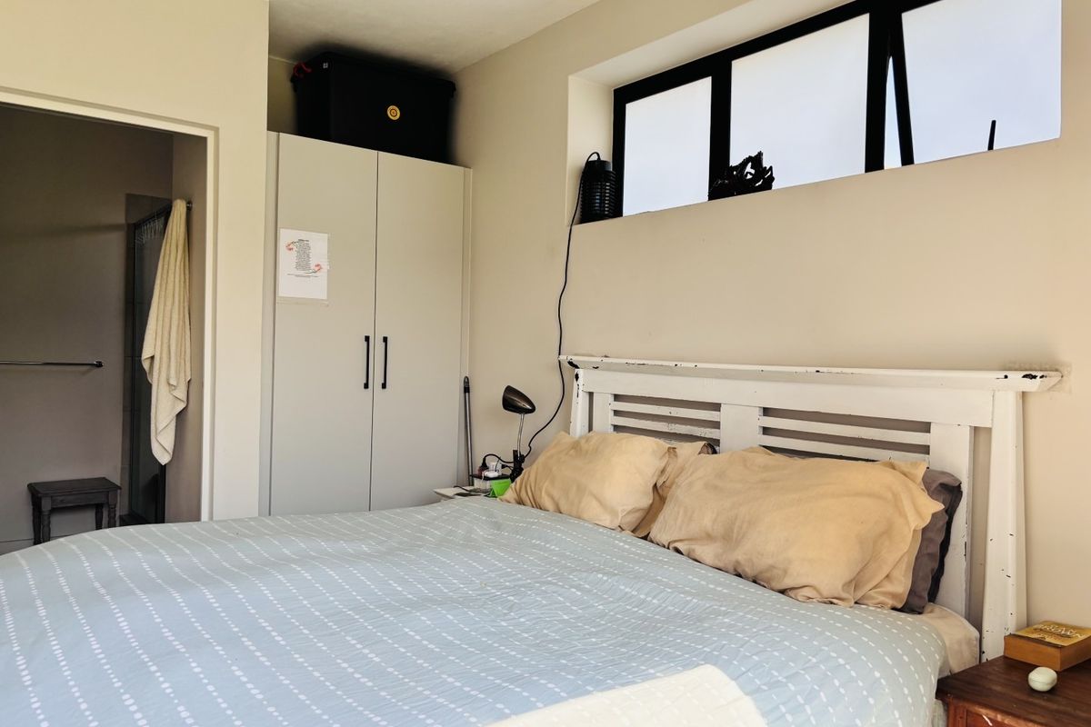 A functional bedroom featuring a built-in wardrobe and a high-level window, providing natural light and storage space.