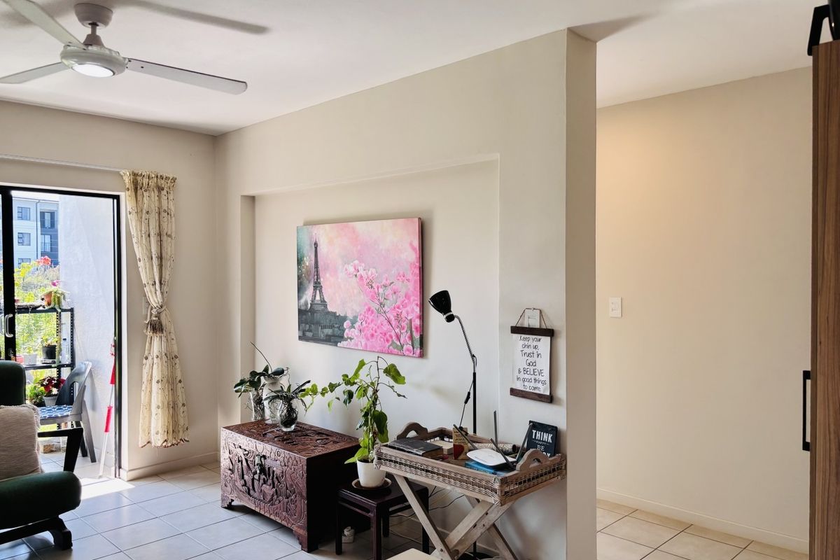 A living area featuring tiled flooring, a ceiling fan, and a sliding glass door leading to a balcony, with a recessed wall niche.