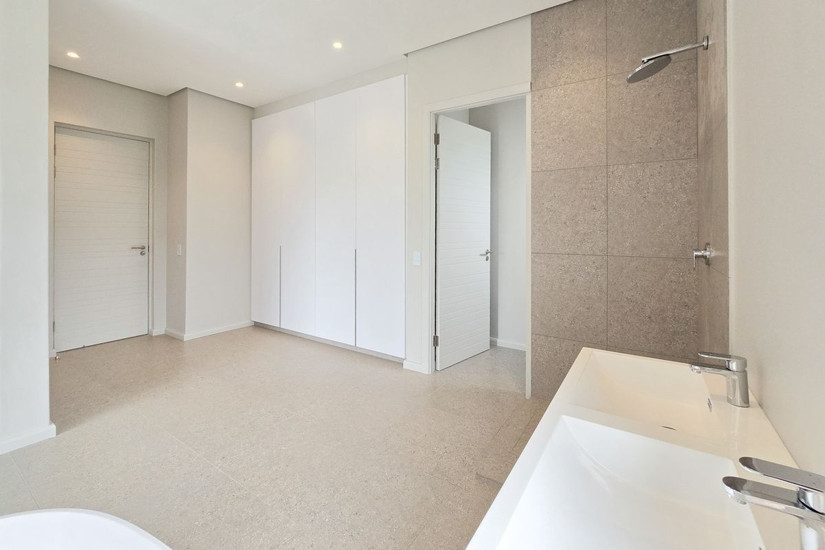 Modern, spacious bathroom featuring a double vanity, walk-in shower, and ample built-in cupboard storage with a clean, neutral aesthetic.