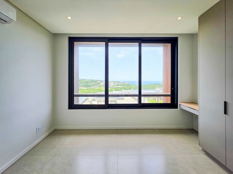 A bright, modern, and empty bedroom featuring tiled floors, built-in cupboards, a built-in desk, air conditioning, and large windows with scenic views.