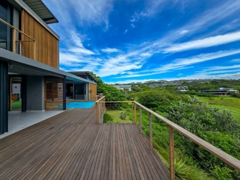 Spacious elevated timber deck featuring a swimming pool, modern timber balustrades, and expansive views over the surrounding landscape.
