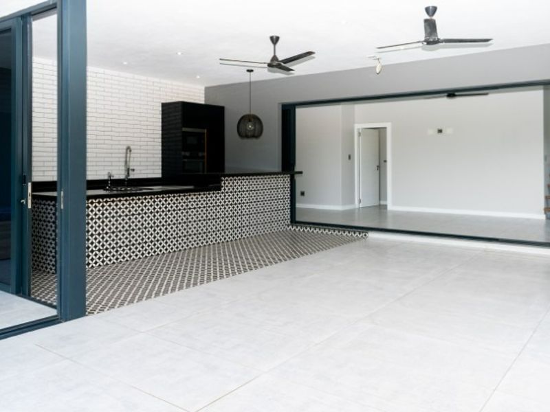 Spacious open-plan kitchen and living area featuring modern cabinetry, a patterned tile island, subway tile backsplash, and large sliding glass doors.