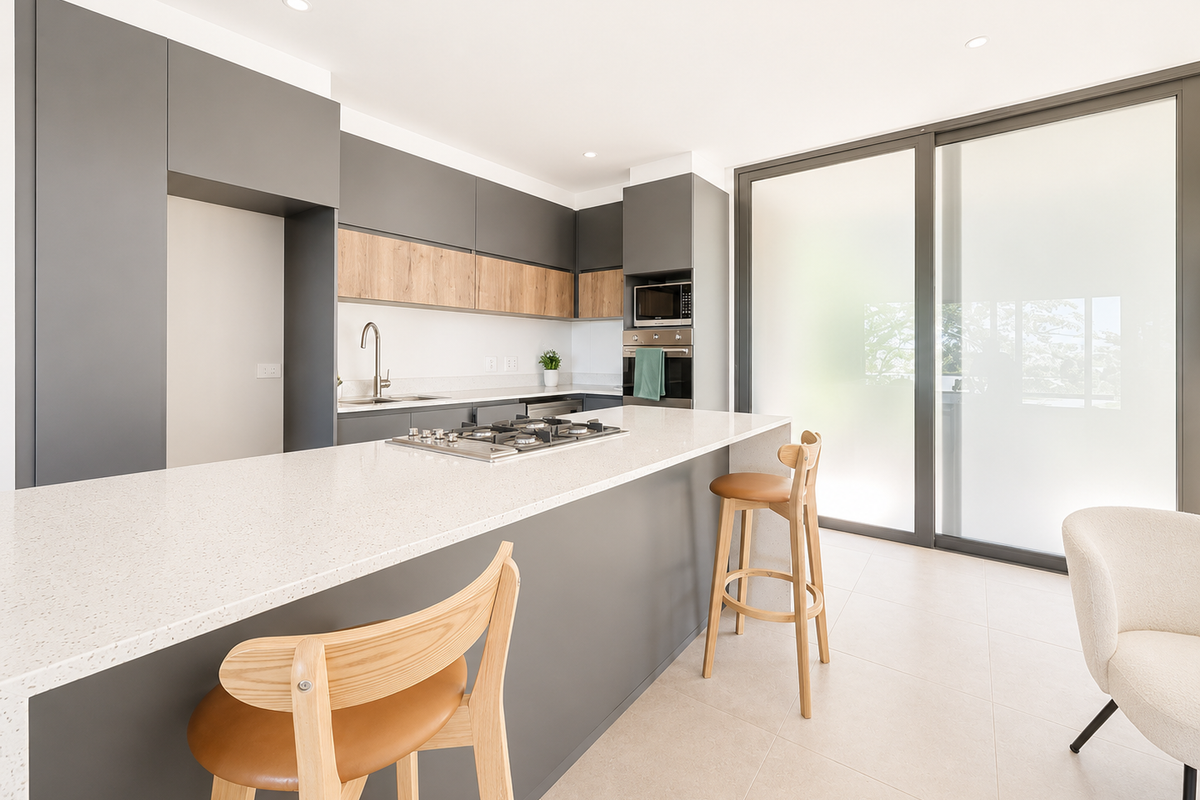 Modern kitchen featuring sleek grey cabinetry, wood-tone accents, quartz countertops, integrated appliances, and large sliding glass doors leading to an outdoor area.